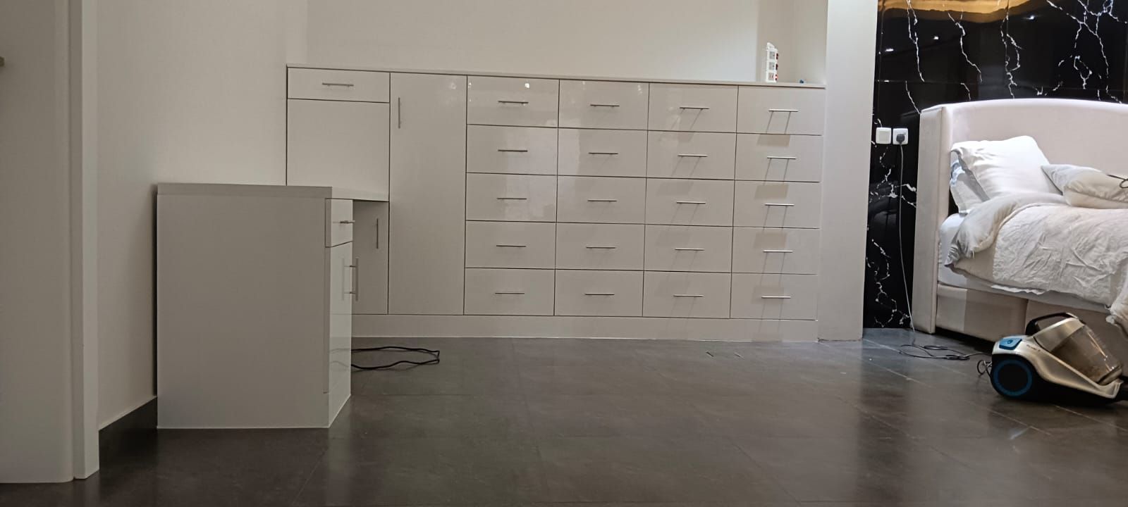A space-maximizing bedroom installation featuring a floating corner study desk smoothly transitioning into a full-height wardrobe system equipped with multi-tier square drawer units. - Photo 2