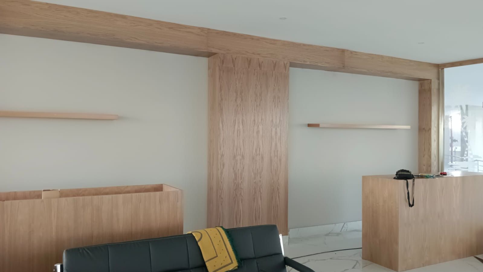 Comprehensive commercial interior woodwork including ash wood wall cladding, structural column wraps, floating shelves, service counters, and geometric grid display plinths. - Photo 2