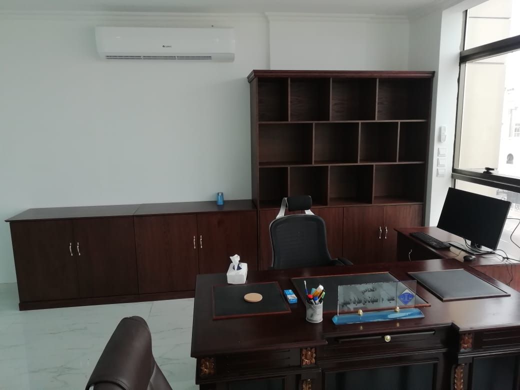 A classic, professional executive office suite featuring a dark mahogany-finished wooden desk paired with a matching large storage cabinet assembly containing lower doors and open upper square shelving grid. - Photo 1