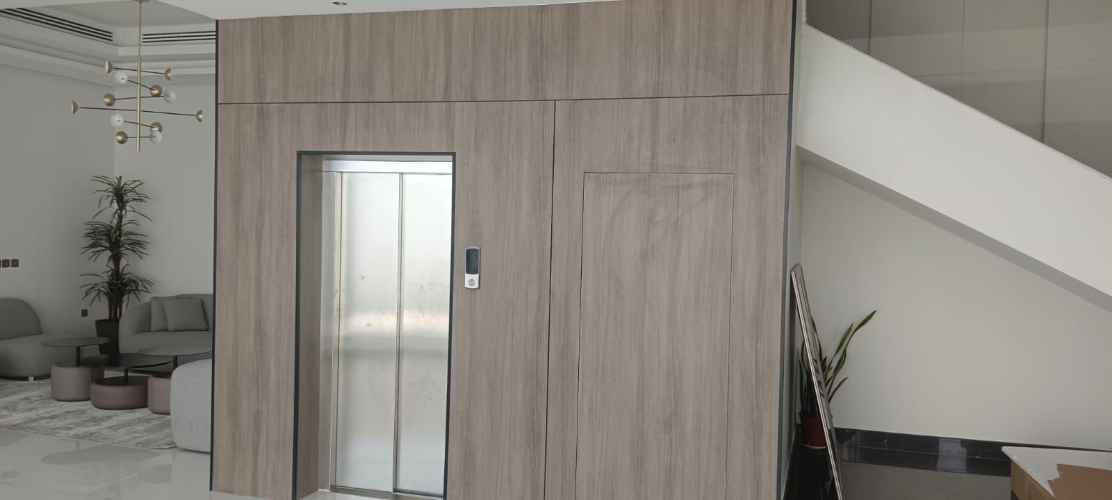 Premium floor-to-ceiling wood veneer wall cladding integrated with flush interior doors and an elevator surround for a seamless architectural finish. - Photo 1