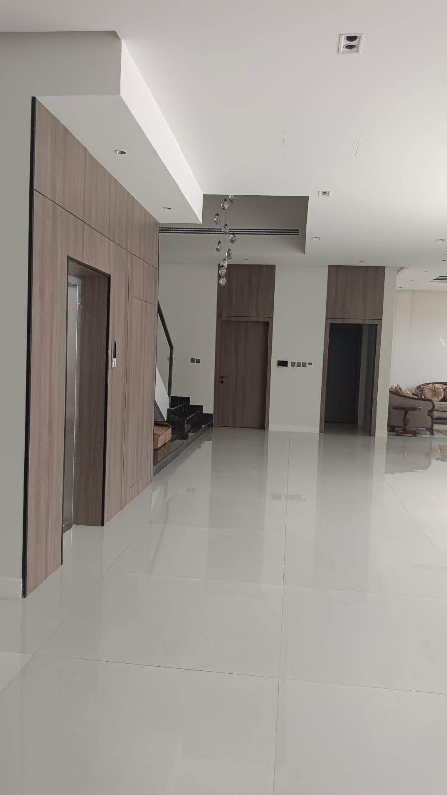 Premium floor-to-ceiling wood veneer wall cladding integrated with flush interior doors and an elevator surround for a seamless architectural finish. - Photo 3