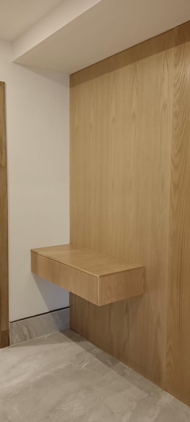 A minimalist wall-mounted television back panel assembly integrated with a low-profile floating media shelf underneath and a matching vertical open-shelf unit tucked into the corner. - Photo 2