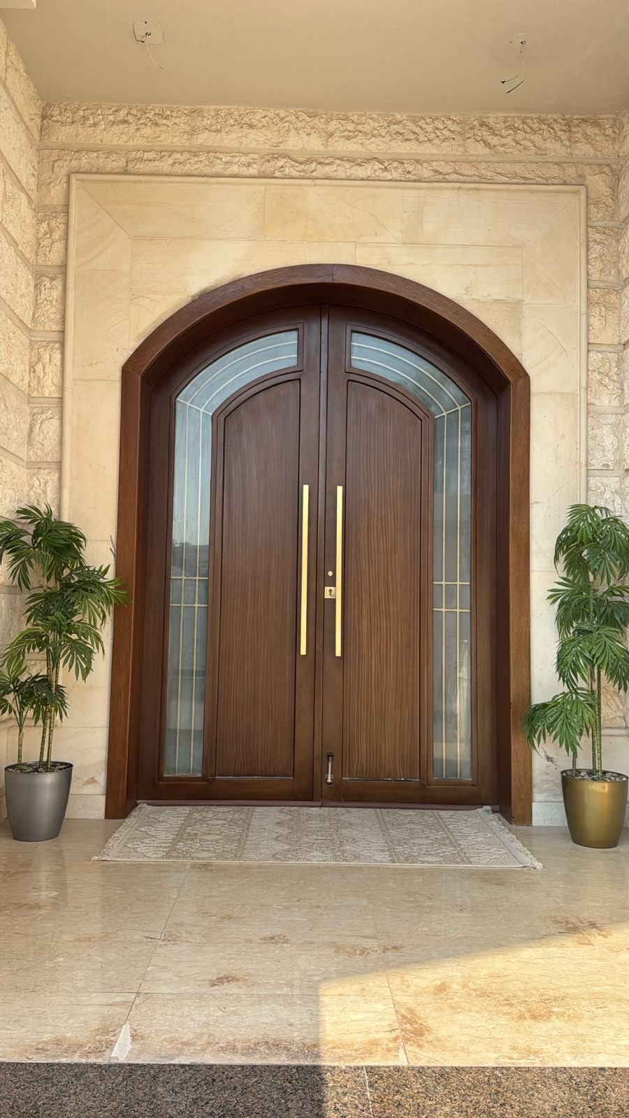 A set of matching modern exterior entryway doors crafted from natural wood panels, including a grand double-door main entrance and a coordinating single-door secondary entry. - Photo 1