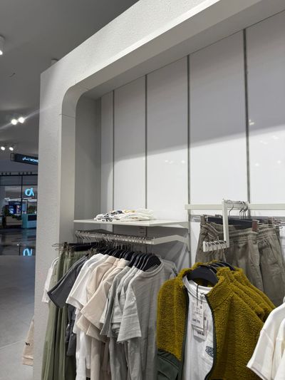 A commercial retail display setup featuring wall-mounted garment hanging rails paired with integrated decorative wall cladding panels.