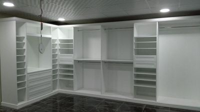 A collection of expansive floor-to-ceiling built-in wardrobes featuring a clean white finish, minimalist linear handles, and optimized internal storage combinations of shelving, drawers, and hanging rods.
